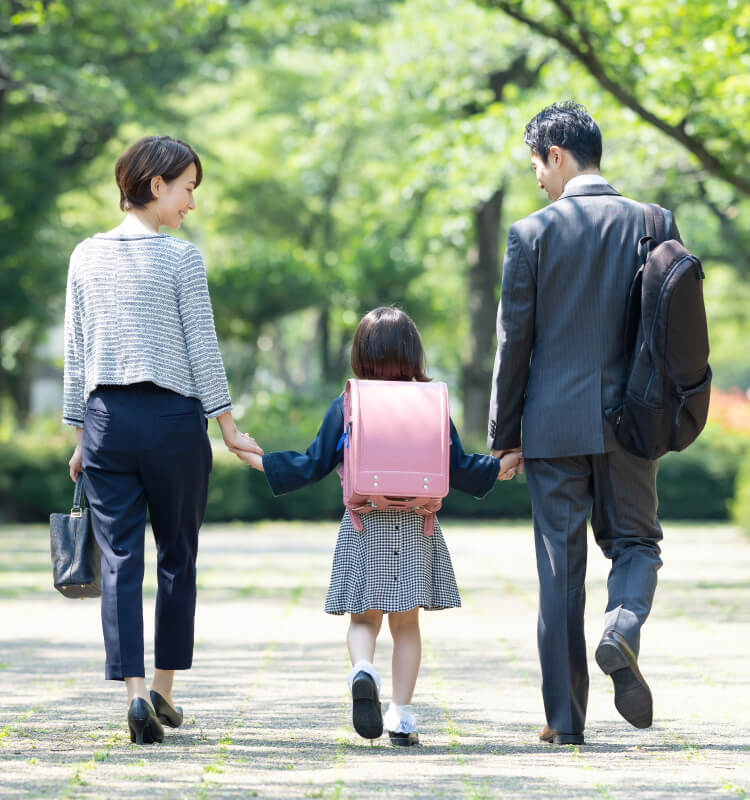 朝、手を繋いで出勤と登校をする家族の後ろ姿